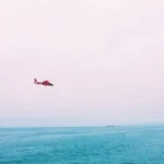 red plane on mid air above sea