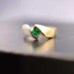 a gold ring with a green stone sitting on a table