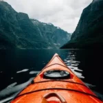 orange canoe on lake surrounding with mountain at daytime