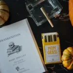 an open book sitting on top of a table next to two pumpkins