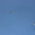 two airplanes are flying in the blue sky