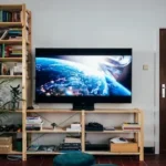 black flat screen tv turned on near brown wooden shelf