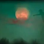 a blurry image of a person standing in front of a full moon