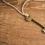 a golden key on a string on a wooden surface