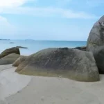 a large rock sitting on top of a sandy beach