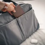 a person holding a wallet in a bag on a bed