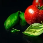 red tomato beside green leaves