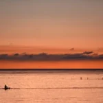 person kayaking during sunset
