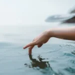 person touching body of water