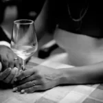 grayscale photo of man holding hand of woman holding wine glass