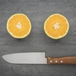 sliced orange fruit beside black handled knife