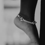 a black and white photo of a person's foot wearing a bracelet