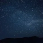 the night sky is filled with stars above a mountain