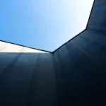 low angle photography of blue glass walled high rise building under blue sky during daytime