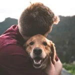 photo of man hugging tan dog