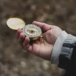 person using white and gold compass