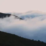 a view of a mountain covered in low lying clouds