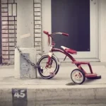 red and white Radio Flyer trike chained on stone post