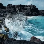 sea waves splash on rock formation at daytime