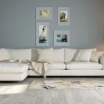 a white couch sitting in a living room next to a lamp