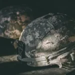 gray and brown camouflage nutshell helmet on table
