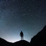 silhouette of man standing on hill during starry night