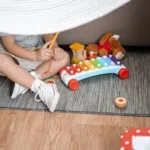 child sitting on floor and playing with xylophone toy