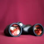 a pair of binoculars sitting on top of a red cloth