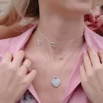 woman in pink blazer wearing silver heart pendant necklace