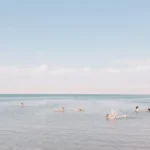 people swimming on sea under cloudy sky