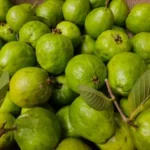 a basket full of limes with green leaves