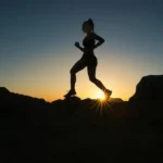 silhouette of man jumping on rocky mountain during sunset
