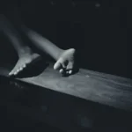 a black and white photo of a person's feet on a table