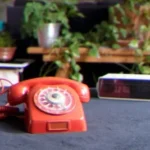 red rotary telephone on gray concrete floor